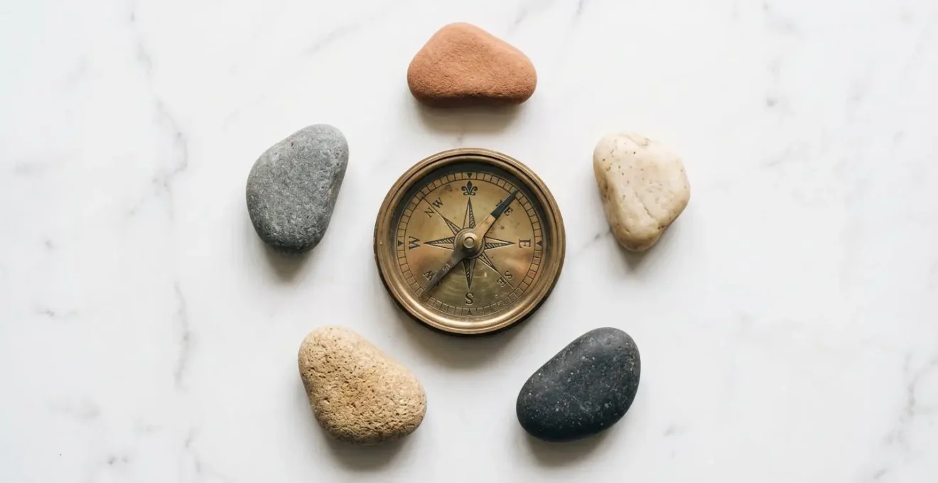 A symbolic representation of personal values, depicted as a compass on a marble surface surrounded by stones, guiding life decisions.