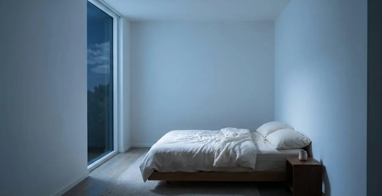Wide environmental shot showing peaceful bedroom at night with emphasis on negative space and restorative atmosphere