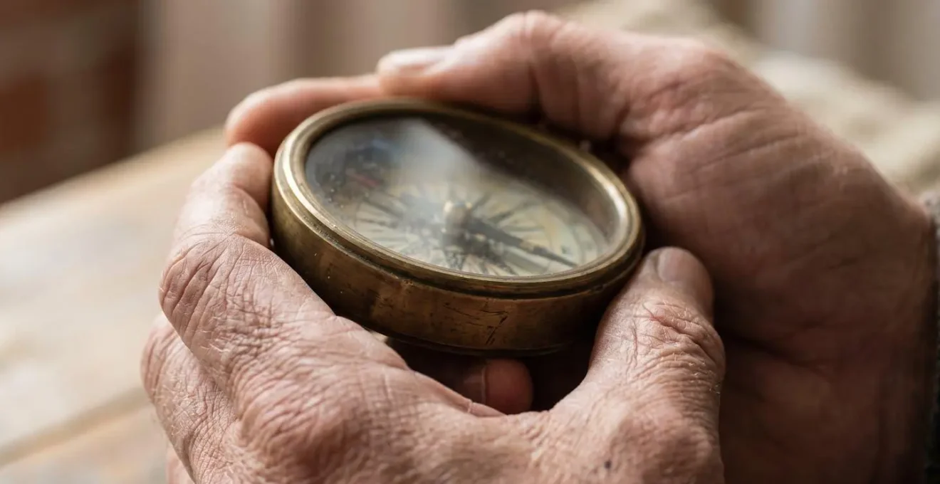 Close-up of hands holding a compass in soft natural light symbolizing inner guidance and emotional awareness