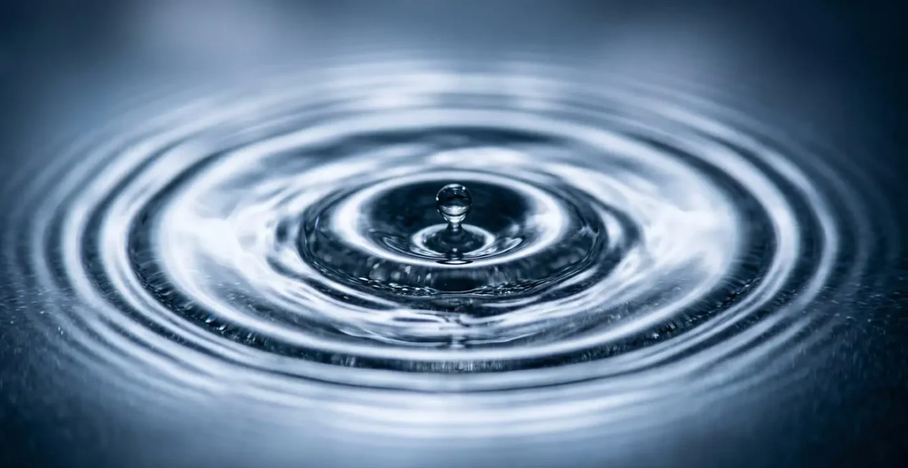 Extreme close-up of water droplet impact creating concentric ripples symbolizing crisis response and psychological resource deployment